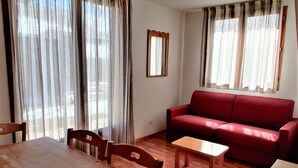 Ein Wohnzimmer mit einem roten Sofa, einem Holzesstisch und Stühlen.