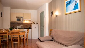 A compact living space with a kitchenette, a dining area with wooden furniture, and a sofa. - 300m from ski slopes, 2nd floor, view mountain/resort, swimming pool, sauna, balcony, parking, tv (Le Dévoluy)