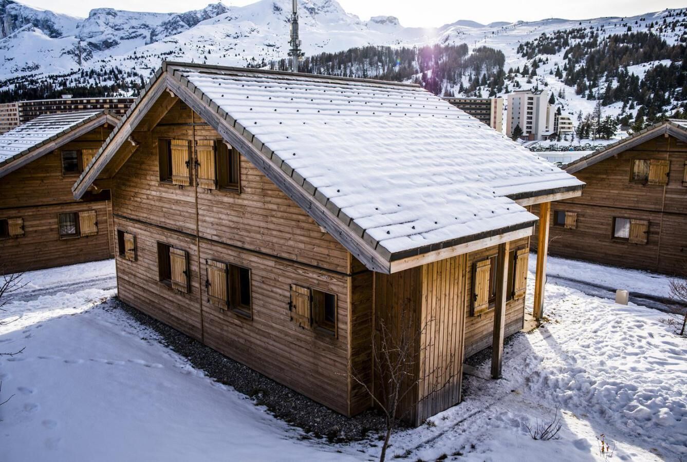 Eine Holzhütte mit geneigtem Dach, mehreren Fenstern und verschneitem Boden.
