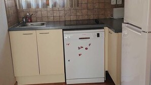 A compact kitchen with a dishwasher, a refrigerator, and a microwave. The kitchen has a tiled backsplash and wooden flooring. - Chalet, 300m from ski slopes, swimming pool, sauna, terrace, parking, tv, ski locker, 42m² (Le Dévoluy)