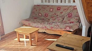 A cozy living room with a sofa, two wooden tables, and a television. - Chalet, 300m from ski slopes, swimming pool, sauna, terrace, parking, tv, ski locker, 42m² (Le Dévoluy)