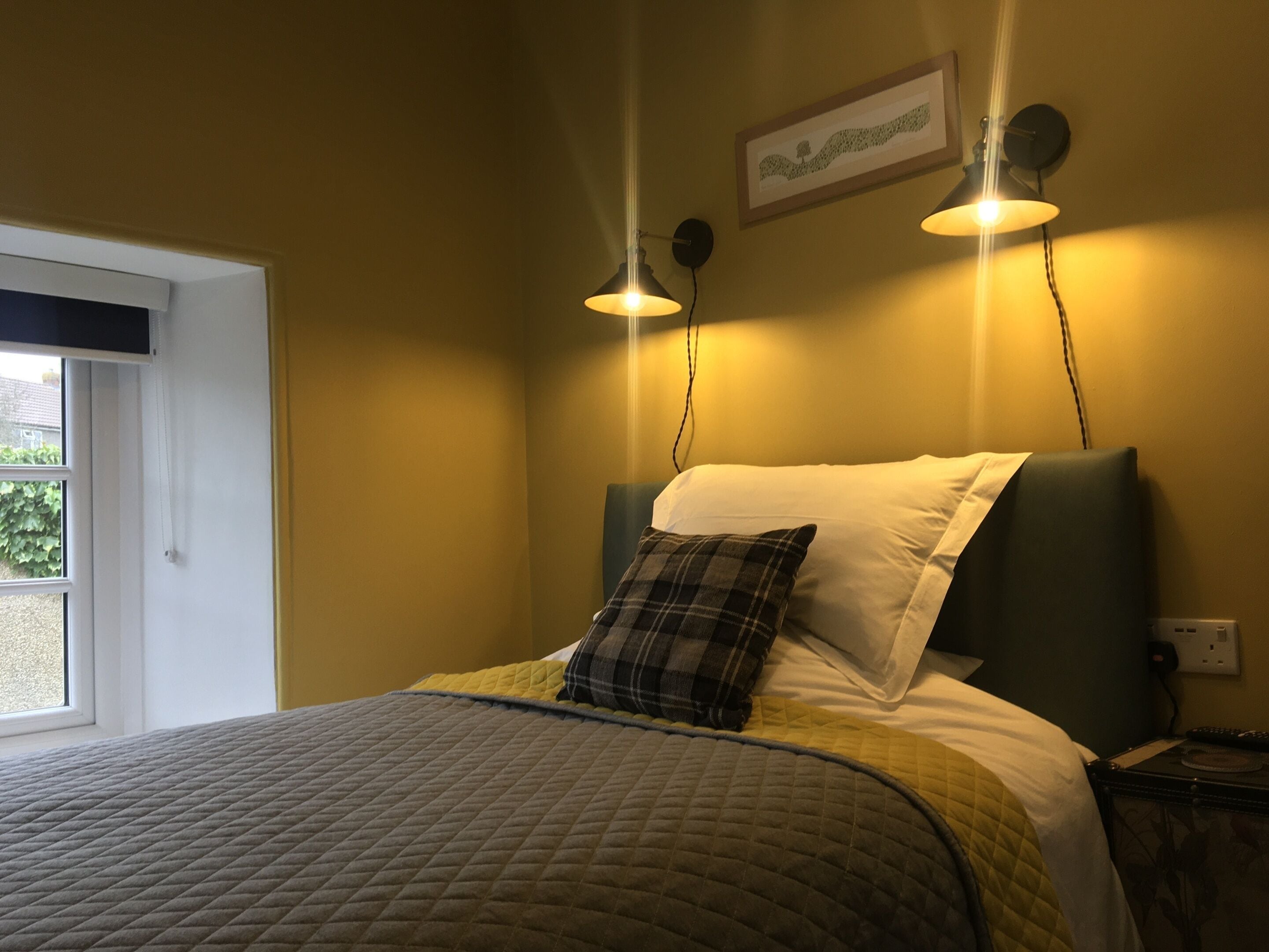 Ein Schlafzimmer mit einem Bett, einem Fenster und zwei Wandleuchten.