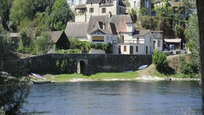 Ein Flussdorf mit traditionellen Häusern, einer Stegbrücke und Booten.