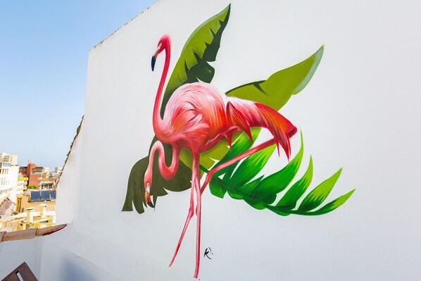 A mural of a pink flamingo with green leaves on a white wall. - MONKÓ BANANA TROPYCAL APARTMENT (Torremolinos)