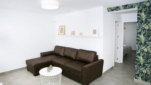 A modern living room with a sectional sofa, a round coffee table, and a wall-mounted shelf with framed pictures.