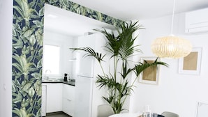 A modern kitchen with white cabinets, a large plant, and a dining area with a round table and chairs.