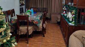 A dining area with a wooden table and chairs, a Christmas tree, and a bookshelf. - Aruba Suite Hotel (Lima)