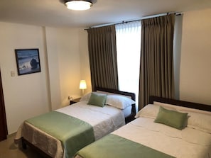 Une chambre d’hôtel avec deux lits, une table de chevet, une lampe et un tableau encadré au mur.