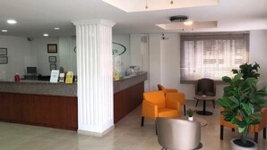 A reception area with a counter, a ceiling fan, and seating arrangements. - Colón Plaza Hotel (Tumaco)