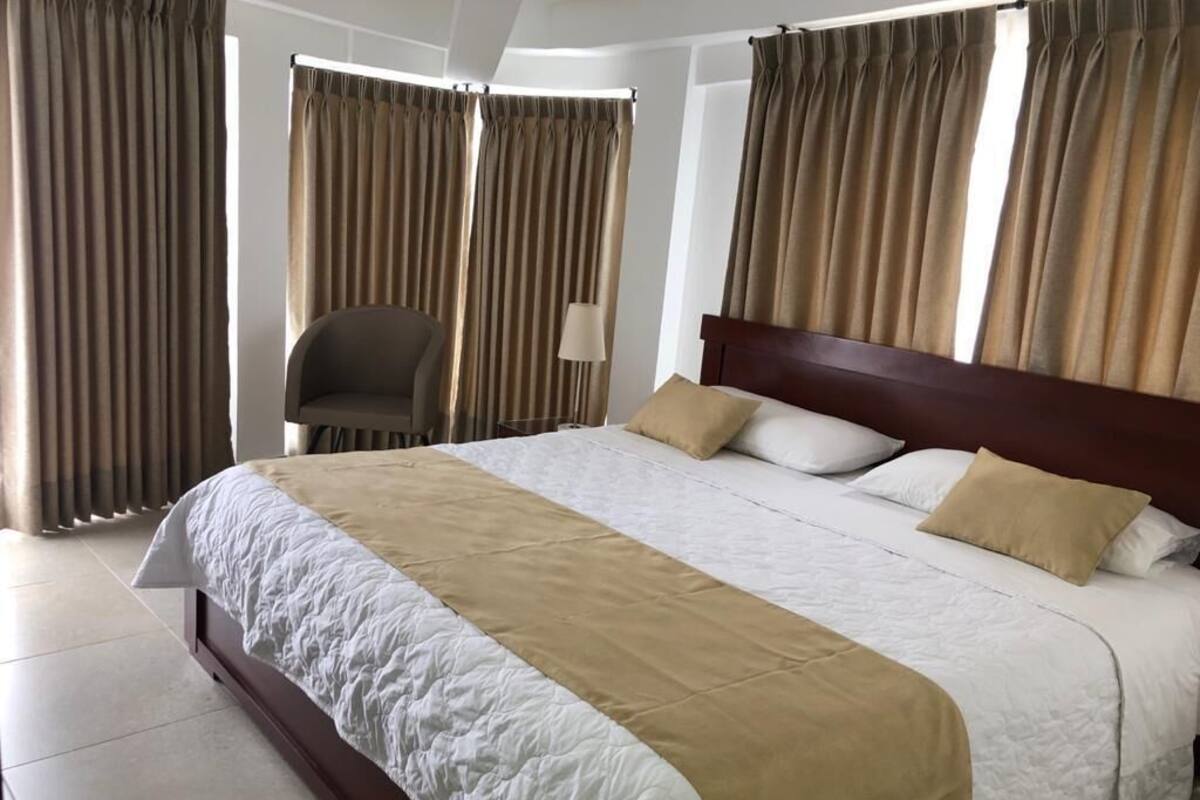 A neatly made bed with a white and beige bedspread, a wooden headboard, and two pillows.
