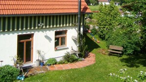 A house with a red-tiled roof, a brick pathway, and a bench in the yard.