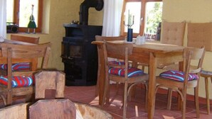 A rustic room with a wooden table and chairs, a large wooden barrel, and a black stove.