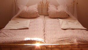 A double bed with a floral bedspread, two matching pillows, and a canopy.