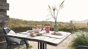 A rustic wooden table set outdoors with a view of the countryside. - De Duynsuites (Callantsoog)