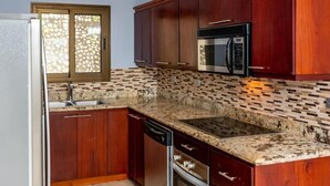 A kitchen with wooden cabinets, a stainless steel microwave, and a granite countertop. - Coastal-Inspired Condo w/ Infinity Pool & Oceanview Terrace (Playa Flamingo)