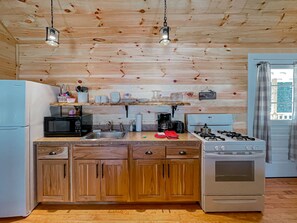 A kitchen with wooden cabinets, a stove, a sink, and a microwave.