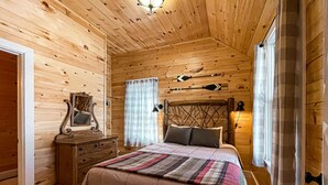 A cozy wooden cabin bedroom with a bed, dresser, and a mirror. - Mrs. Otis's Cabin with Woodland View (Paul Smiths)