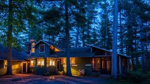 A cabin with a front porch, a visible door, and a small attached structure. - Mrs. Otis's Cabin with Woodland View (Paul Smiths)