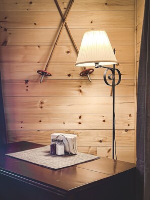 Pared de madera con una lámpara colgante y una pequeña mesa con saleros y pimenteros.