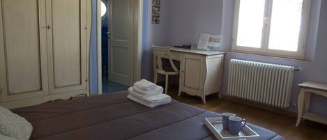 A bedroom with a bed, a desk, and a window.