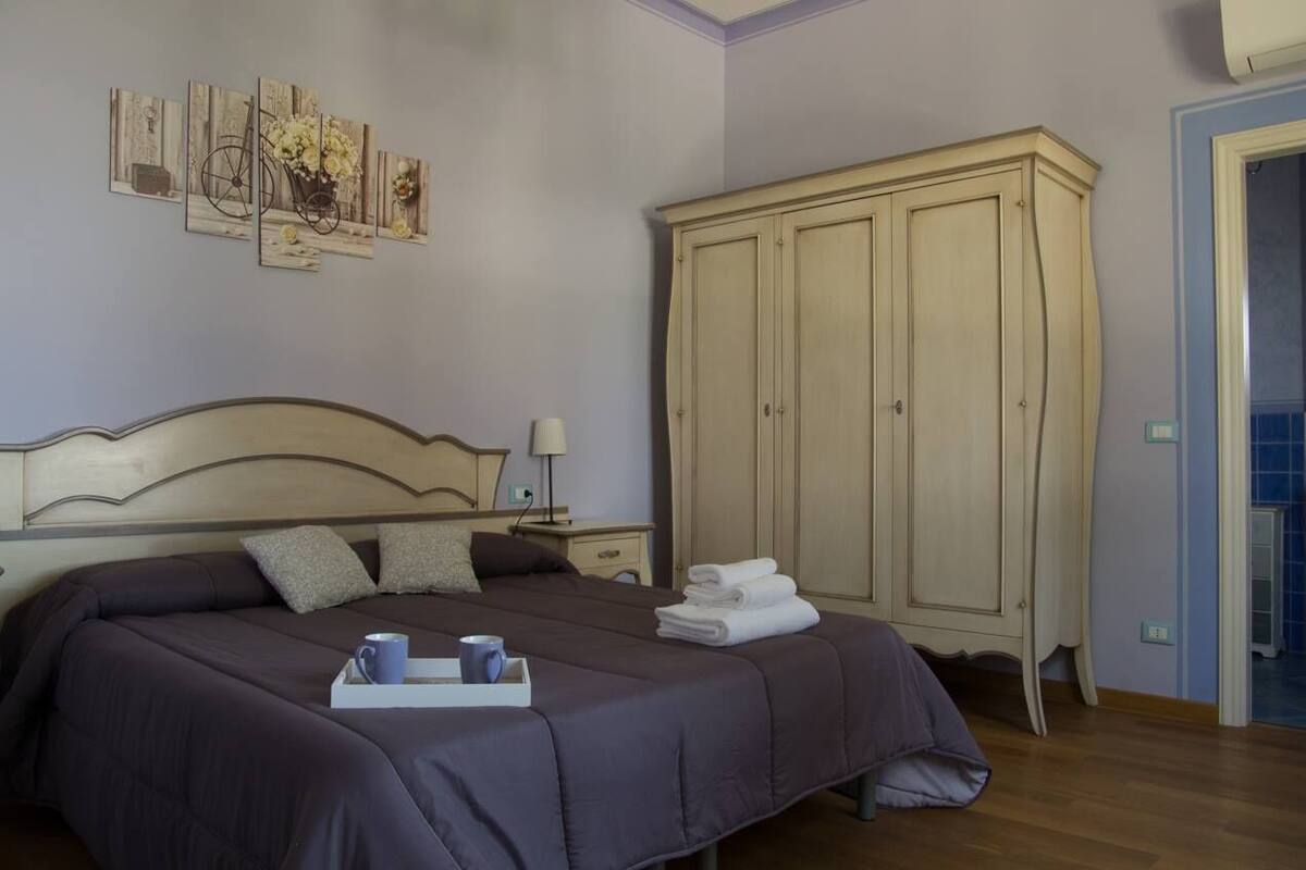 Quarto com uma cama grande, um guarda-roupa e uma obra de arte na parede.