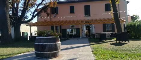 A building with a covered patio, outdoor seating, and a large barrel planter.
