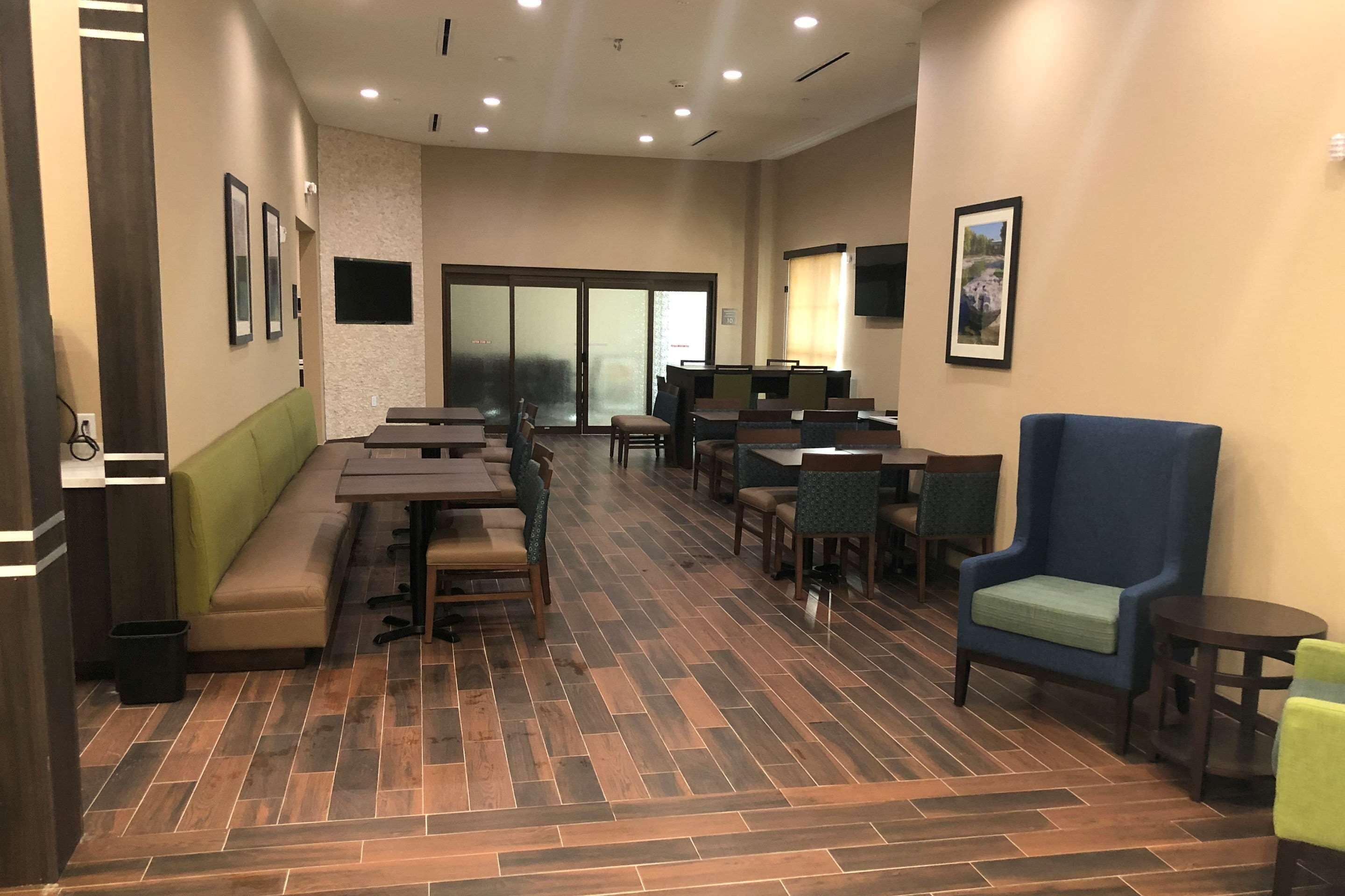 Amplio espacio interior con diversas opciones de asientos, incluyendo mesas y sillas, un sofá verde y un sillón azul.