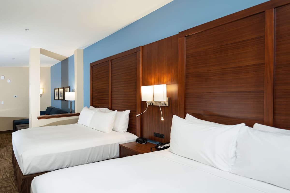 Una habitación de hotel con dos camas, cabeceros de madera y lámparas de noche.