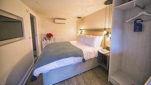 Habitación de hotel con cama, mesita de noche y armario.