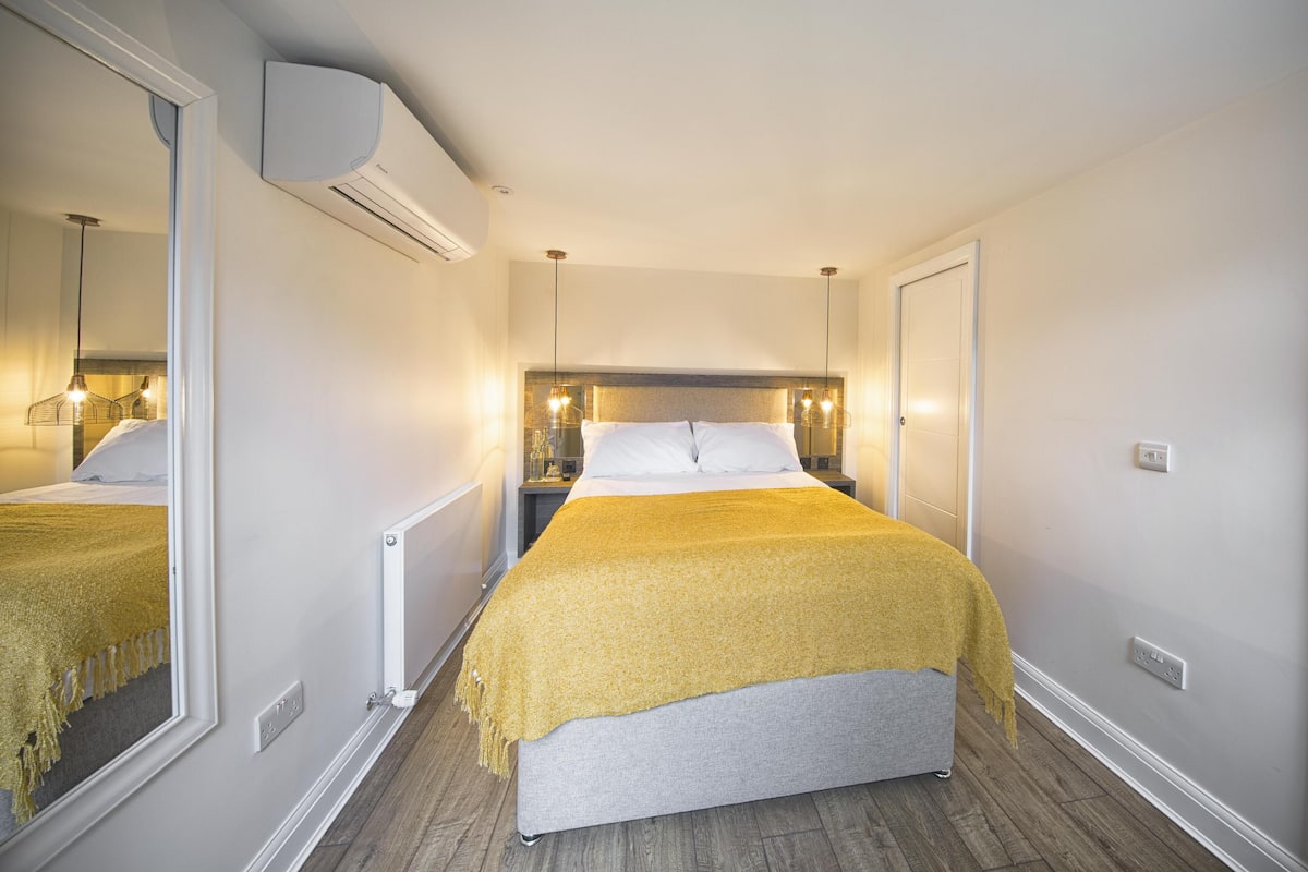 Une chambre d’hôtel équipée d’un lit, de tables de chevet, d’un miroir et d’un appareil de climatisation.