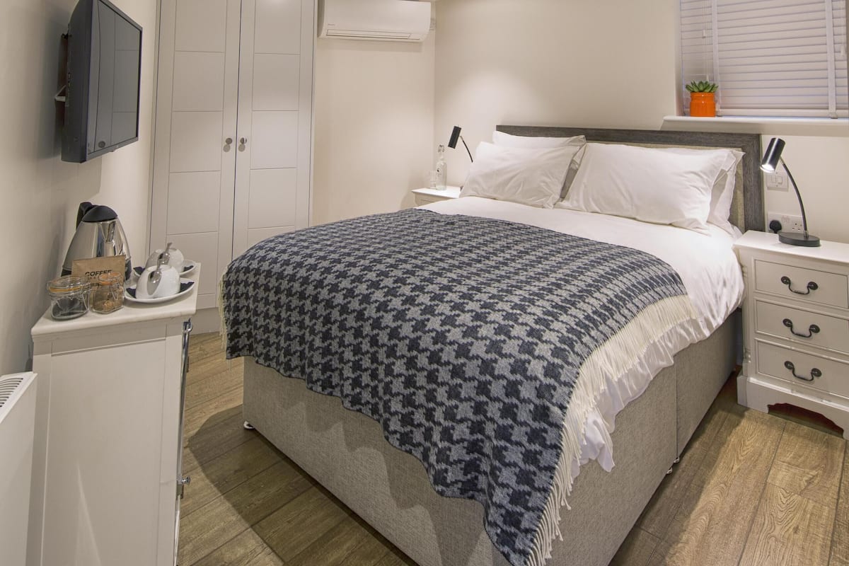 Une chambre à coucher avec un lit, des tables de chevet, une armoire et un téléviseur fixé au mur.