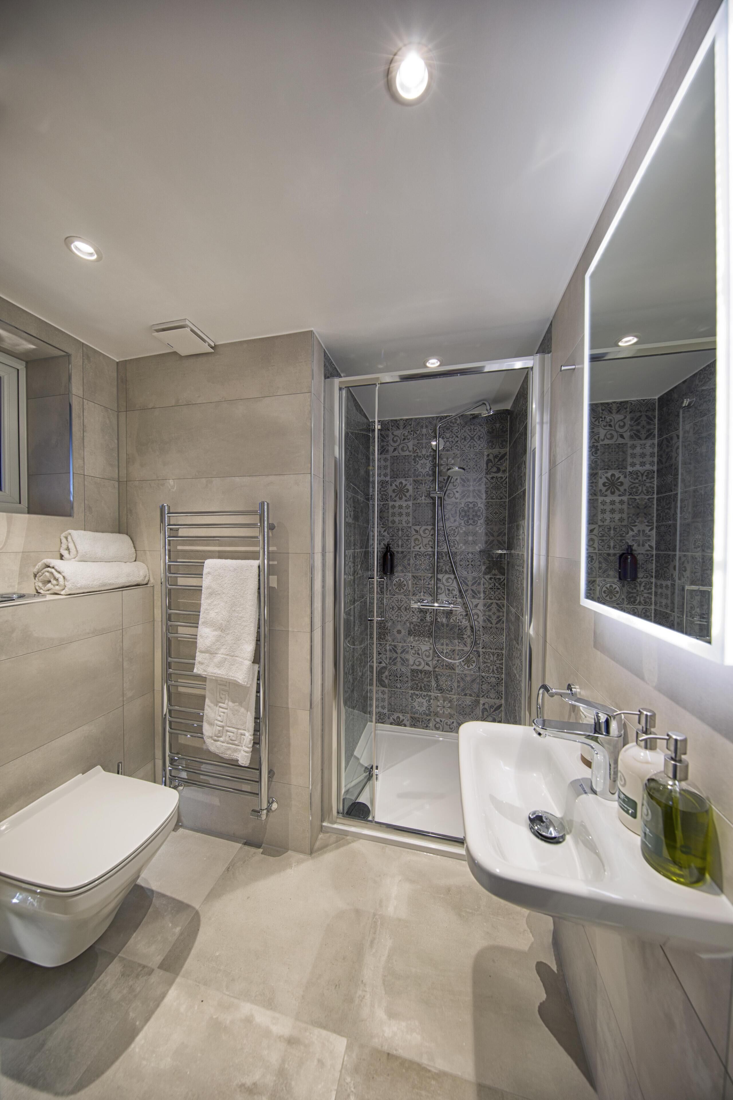 A modern bathroom with a glass-enclosed shower, a white sink, and a large mirror.