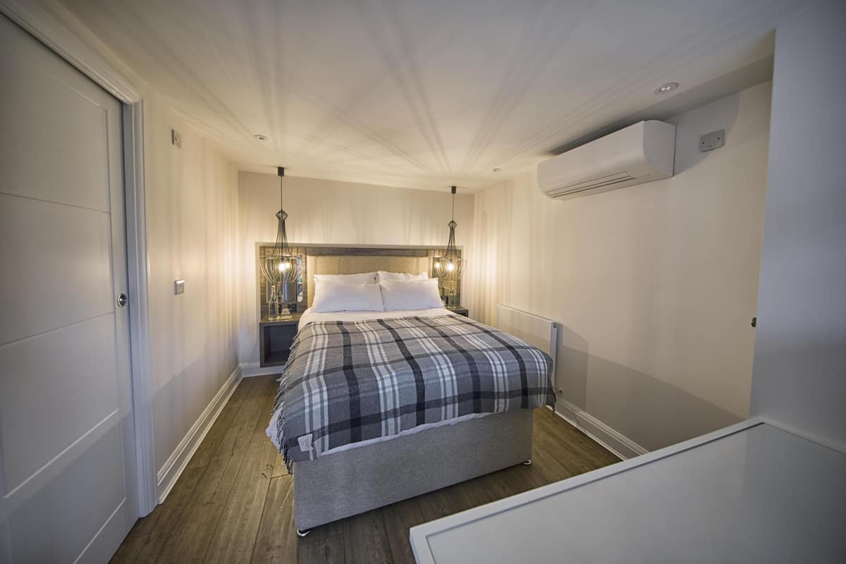 Une chambre à coucher avec un lit, des tables de chevet et un appareil de climatisation.