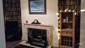 A living room with a fireplace, a bookshelf, and a framed picture on the wall. - Wexford Townhouse (Wexford)