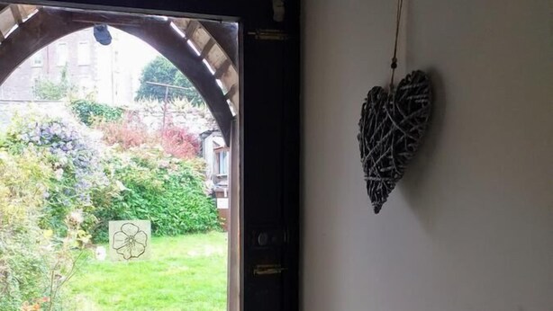 A door with a view of a garden, a blue pot, and a heart-shaped decoration on the wall. - Wexford Townhouse (Wexford)