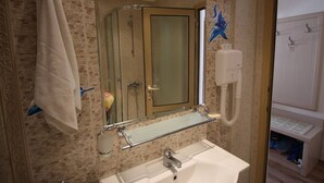 Un baño con cabina de ducha de vidrio, un lavamanos blanco y un perchero para toallas.