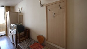 Una habitación de hotel con cama, escritorio, silla, armario y televisor.
