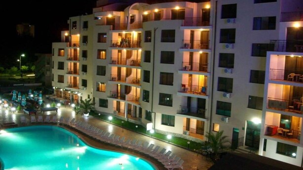 Un hotel de varios pisos con balcones, piscina y zona de estar al aire libre.