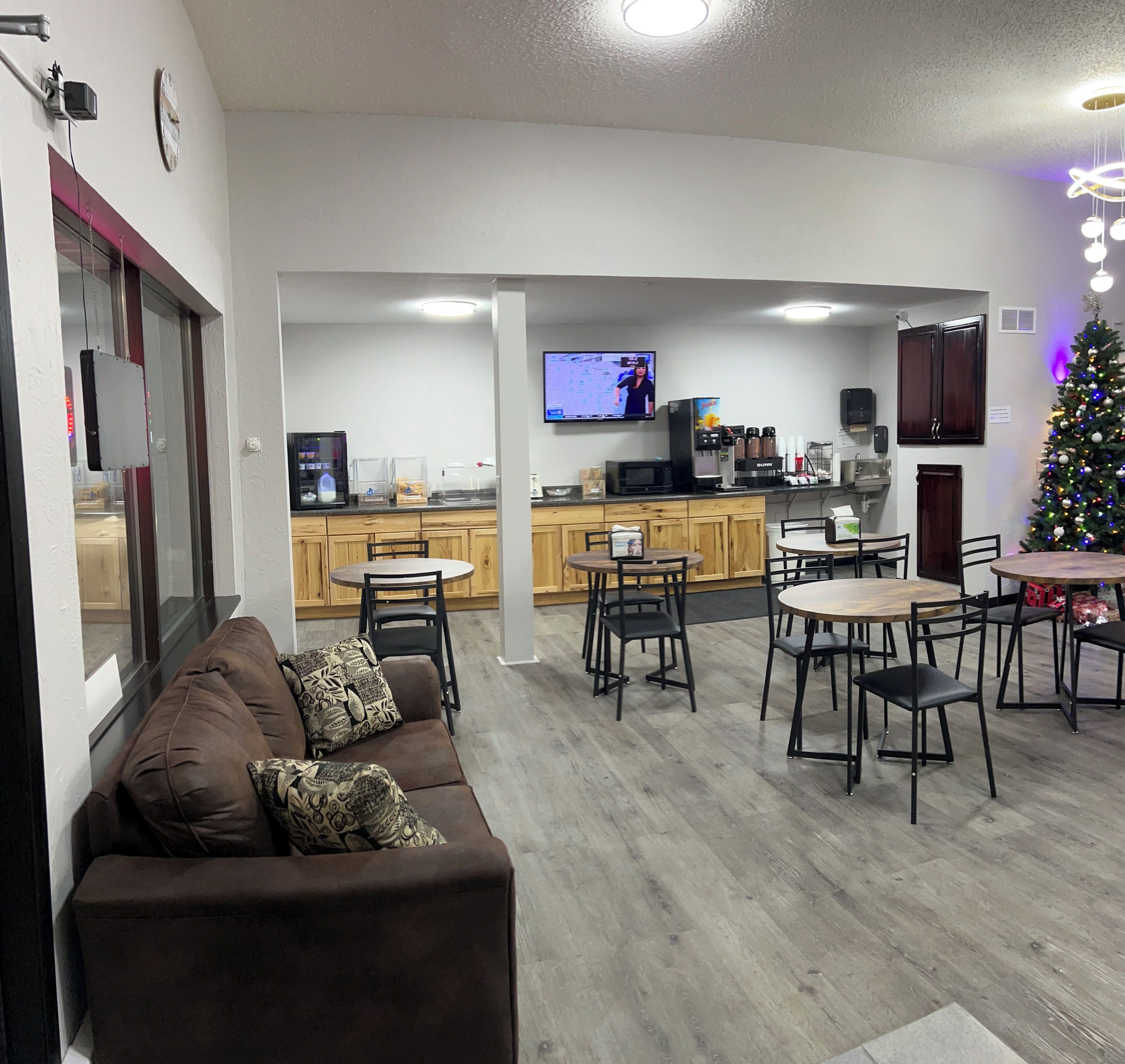 A living room with a brown sofa, a TV, and a kitchen area with wooden cabinets and a refrigerator.