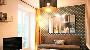 Ein Wohnzimmer mit Flachbildfernseher, einer Couch, einem Couchtisch und einer Wand mit Muster.