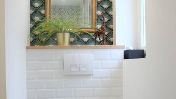 Een badkamer met een wit toilet, een spiegel met gouden lijst en een behang met patroon.