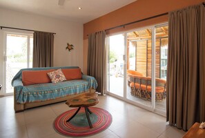 A room with a sofa, a small round table, and a view through a glass door to an outdoor seating area. - WATERFRONT COMPLETE GROUND FLOOR 73m2 WITH PRIVATE TERRACE & INFINITY POOL (Barra de Navidad)