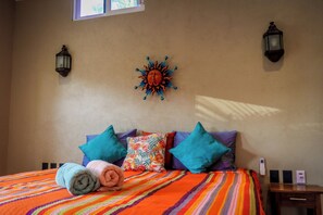 A hotel room with a bed, pillows, a wall-mounted sun decoration, and two wall-mounted lamps. - WATERFRONT COMPLETE GROUND FLOOR 73m2 WITH PRIVATE TERRACE & INFINITY POOL (Barra de Navidad)