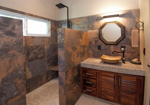A bathroom with a stone wall, a wooden vanity, a freestanding sink, a shower, and a window. - WATERFRONT COMPLETE GROUND FLOOR 73m2 WITH PRIVATE TERRACE & INFINITY POOL (Barra de Navidad)