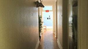 Un couloir étroit doté d’un plancher en bois, de murs blancs et orné d’une tête de cerf fixée au mur.