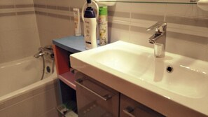 Een bad/douchecombinatie, een haardroger, toiletpapier