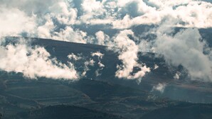 Een bergachtig landschap met een vallei en verspreide wolken.