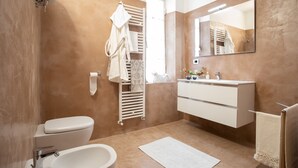 Een moderne badkamer met een wit toilet, een wastafel, een handdoekhouder en een spiegel.