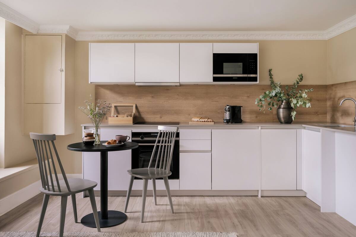 Una cocina moderna con armarios blancos, un microondas negro y una encimera de madera.