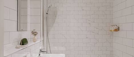 A modern bathroom with a white sink, a shower, and a mirror.